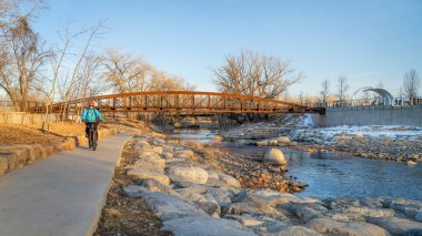 Erkek bisikletçi kış günbatımı manzarasında bisiklet sürüyor - Fort Collins, Colorado 'da Poudre River Trail şehir merkezindeki Whitewater Park, dinlenme ve gidiş-dönüş konsepti