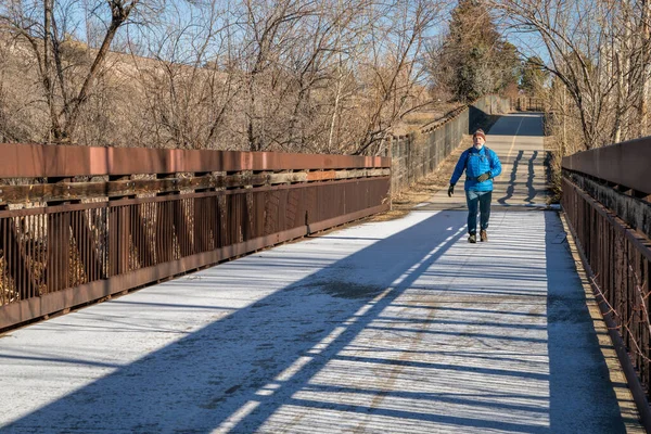 在科罗拉多州柯林斯堡 一个背着背包的老人正走在一条被霜冻覆盖的自行车道和人行天桥上 — 图库照片