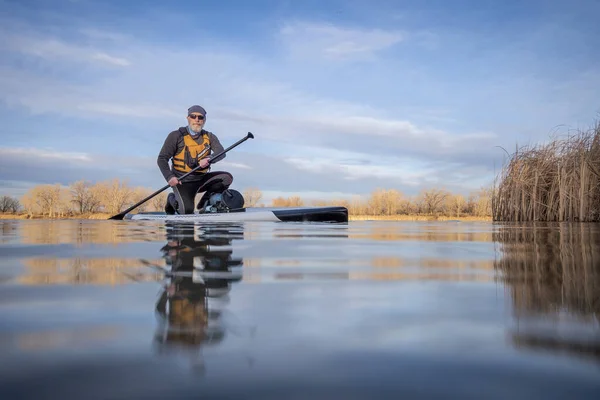 在科罗拉多州的冬季或春季 资深划桨手和他的划桨板在湖上 青蛙的视角 部分水下动作相机 — 图库照片