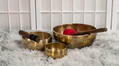 Kabarık bir halının üzerinde tokmaklı el yapımı Tibet şarkı kaseleri, şifa, rahatlama ve meditasyon için ses terapisi