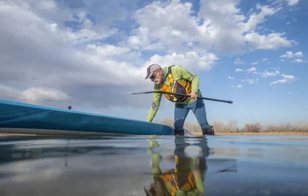 コロラド州の冬または早春の湖の上のシニアパドラーと彼のパドルボード カエルの視点 部分的に水中アクションカメラ — ストック写真