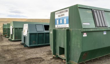 Fort Collins, CO, ABD - 13 Nisan 2023: Geri dönüşüm merkezi - Larimer County çöp sahasında talimat levhaları olan bir sıra yeşil çelik konteynır.