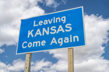 Kansas 'tan ayrılıyoruz, tekrar gelin. Bulutlu gökyüzüne karşı otoyolda yol tabelası var.