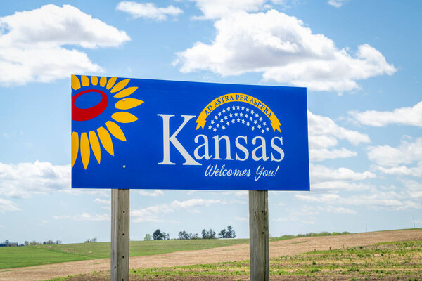 Kansas welcomes you - welcome road sign with a popular latin phrase ad astra per aspera (сквозь трудности к звездам), driving and travel concept