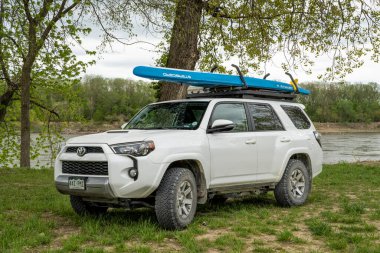 Lupus, MO, ABD - 22 Nisan 2023: Toyota 4Runner SUV Bahar mevsiminde Mlssouri Nehri kıyısındaki çatı raflarında bir performans ile kürek çekme tahtası (Sancak Waterline)..