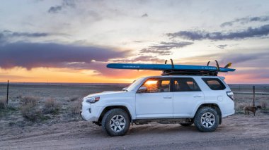 Julesburg, CO, ABD - 20 Nisan 2023: Toyota 4Runner SUV Doğu Colorado 'da prarie üzerinden gün batımına karşı ayakta kürek çekme (Sancak Waterline) performansı ile.