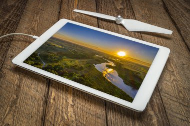 Nebraska Ulusal Ormanı 'ndaki Nebraska Kum Tepeleri' nden geçen Kasvetli Nehir üzerinde gün doğumu dijital tablet üzerindeki bir tatil görüntüsünü inceliyor.