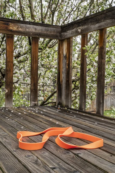 heavy duty resistance exercise band for fitness and rehabilitation on wooden backyard deck, springtime scenery