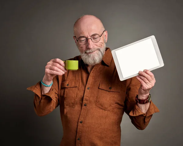 Sorridente Homem Sênior Está Bebendo Café Mostrando Tablet Digital Branco — Fotografia de Stock