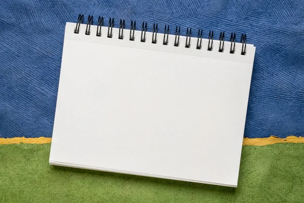Blanco Spiraal Schetsboek Met Witte Pagina Tegen Kleurrijk Abstract Papierlandschap — Stockfoto