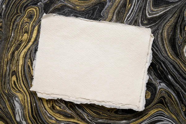 Arkusz Białego Papieru Szmatławcowego Khadi Przeciwko Abstrakcyjnemu Czarno Złotemu Papierowi — Zdjęcie stockowe
