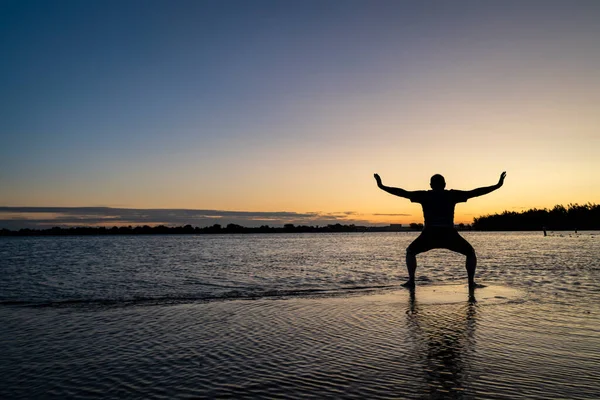 浅瀬に立ち チゴンや太極拳の動きを練習する男の日の出のシルエット コロラド州北部のボイド湖州立公園 — ストック写真
