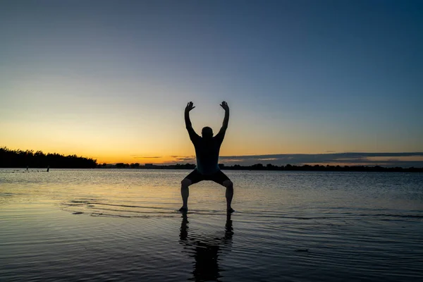 浅瀬に立ち チゴンや太極拳の動きを練習する男の日の出のシルエット コロラド州北部のボイド湖州立公園 — ストック写真