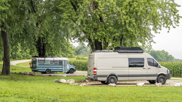 Blackwater, MO, USA - August 4, 2023: Mercedes Sprinter camper van and a camper converted from old school bus are boondocking on shore of Lamine River at Roberts Bluff Access.