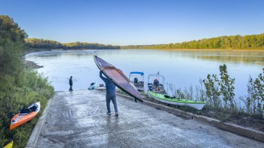 Hartsburg, MO, ABD - 7 Ekim 2023: Ayağa kalk kürekçi, gün doğumunda Missouri Nehri 'nde bir gezi ya da yarış için kayık rampasında kürek çekiyor..