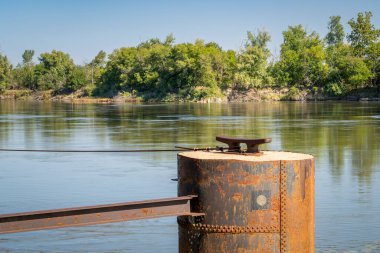Brownville, Nebraska 'daki Missouri Nehri' ndeki mavnalar için bir kramponu olan paslı demirleme yığını.