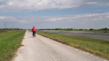 Yalnız bisikletçi çakıllı bir bisiklet turu yapıyor - Illinois Granite City yakınlarındaki Kayalık Kanal Zinciri boyunca bisiklet sürüyor.
