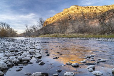 Gün batımı ışığı Belvue Kubbesi 'nin kumtaşı uçurumunda ve kuzey Colorado' daki Poudre Nehri 'nde.