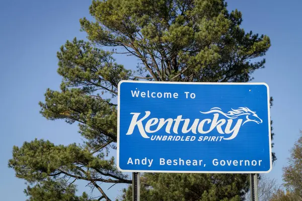 Kentucky 'ye hoş geldiniz, dizginlenemez Ruh. Arka planda çam ağacı olan Tennessee eyalet sınırında yol işareti..