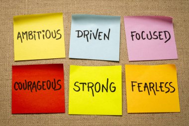 ilham verici güç sözcükleri - hırslı, odaklanmış, cesur, güçlü ve korkusuz - çuval bezi tuvaline karşı yapışkan hatırlatma notları