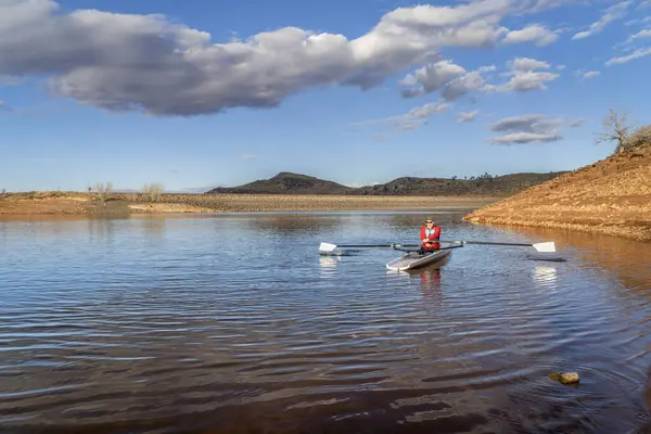 シニア男性は沿岸のローイングシェルを漕いでいます コロラド州北部の秋や冬の景色のホースペット貯水池 — ストック写真