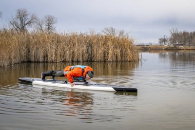 Son sınıf erkek raketçi Colorado 'da bir gölde, kış ya da sonbahar manzarasında raket üzerinde şınav çekiyor.