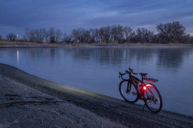 Kuzey Colorado 'da kış alacakaranlığında donmuş bir gölün kıyısında çakıl bisikleti.