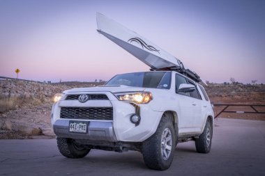 Fort Collins, CO, ABD - 21 Aralık 2023: Kürek kabuklu Toyota 4runner SUV, LiteRace 1x Liteboat tarafından çatı raflarında Horsetooth Reservoir - sonbahar ya da kış alacakaranlık manzarası.