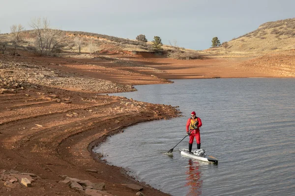 コロラド州 Horsetooth 貯水池でドライスーツで男性カヌーを漕ぐ人のパドリングを冬スタンド — ストック写真