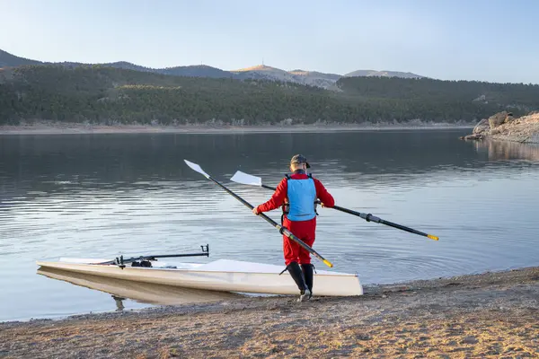 科罗拉多州北部秋天或冬季风景中 资深男子划艇手 带着海岸划艇壳和斧头桨在卡特湖畔划桨 — 图库照片