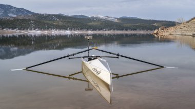 Lothe, CO, ABD - 6 Şubat 2024: Kıyı kürek kabuğu, Liteboat tarafından Literace 1x, kuzey Colorado 'daki Carter Gölü kıyılarında bir ayna ve su geçirmez çanta.
