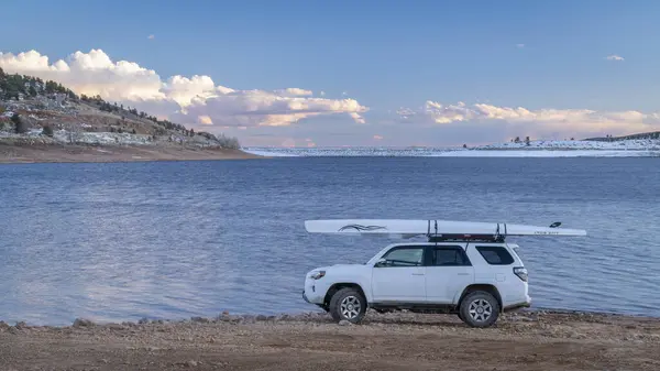 ラブランド アメリカ 2024 冬の夕暮れにコロラド州北部のカーター湖の岸にラックにライトボートのローイングシェルを持つトヨタ4ランナーSuv — ストック写真