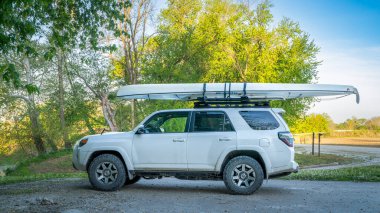 Blackwater, MO, ABD - 22 Nisan 2024: Toyota 4Runner SUV İlkbahar manzarasında Lamine Nehri kıyısında çatı raflarında bir keşif kanosu ile.