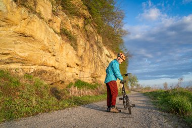 Steamboat Trace 'de bisiklet süren son sınıf erkek bisikletçi. Peru, Nebraska yakınlarındaki terk edilmiş bir demiryolundan dönüşmüş bisiklet yolu. İlkbahar sabahı manzarası.