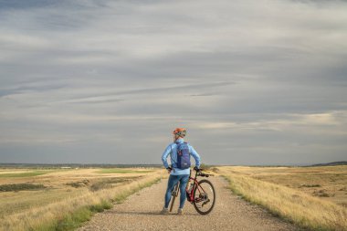 Colorado eteklerinde bir çiftlik yolunda çakıl bisikletli bir erkek bisikletçi.