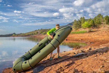 Yaşlı erkek kürekçi Colorado 'da bir göl kıyısındaki şişme bir yük gemisine hava ekliyor. Yaz aylarında Horsetooth Reservoir' da.