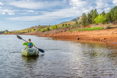 Son sınıf öğrencisi erkek, Colorado 'daki Horsetooth Barajı' nda şişme bir yük gemisiyle kürek çekiyor.