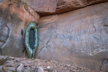 Colorado 'da Horsetooth Reservoir sahilinde kumtaşı uçurumunda küreği olan şişme bir yük gemisi.