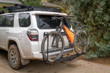 Fort Collins, CO, USA - October 30, 2024: 600x Priority adventure mountain bike on the back of Toyota 4Runner SUV mounted with Kuat piston hitch rack. clipart