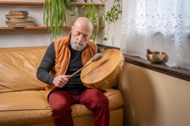 Son sınıf öğrencisi yerli Amerikan tarzında davul çalıyor. Evde vurucu, yaşam tarzı ve hobi konsepti olan bir şaman davulu.