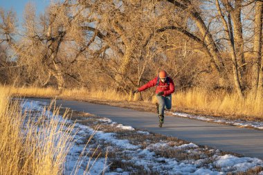 Sırt çantalı son sınıf öğrencisi Colorado 'daki Poudre Nehri' nde asfalt bir bisiklet yolunda paten kayıyor. Gün batımında sonbahar veya kış manzarası.