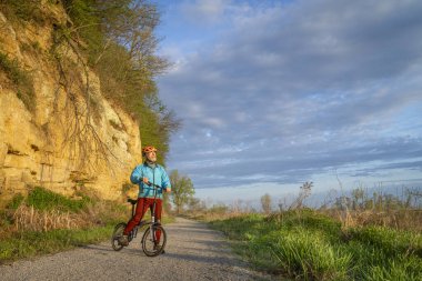 Steamboat Trace 'de bisiklet süren son sınıf erkek bisikletçi. Peru, Nebraska yakınlarındaki terk edilmiş bir demiryolundan dönüşmüş bisiklet yolu. İlkbahar sabahı manzarası.