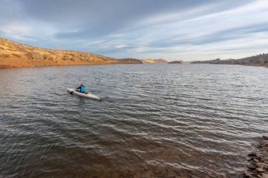 Rocky Dağları eteklerindeki Horsetooth Rezervuarı 'nda kış manzarasında yalnız bir kürekçi.