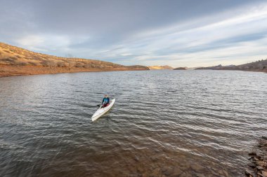 Rocky Dağları eteklerindeki Horsetooth Rezervuarı 'nda kış manzarasında yalnız bir kürekçi.