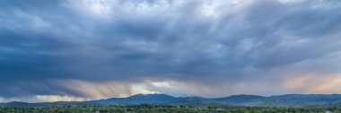 dramatic storm clouds at dusk over Rocky Mountains and lake in northern Colorado clipart