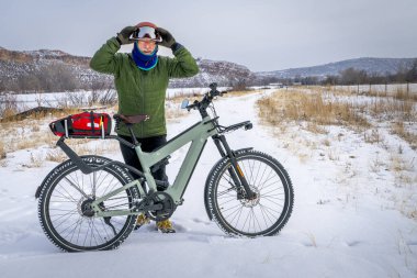 Colorado eteklerinin soğuk kış manzarasında bisiklet turu yapan yaşlı bir bisikletçi.
