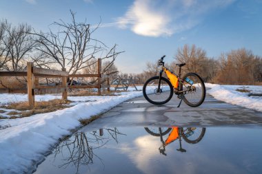 Colorado 'da Greeley yakınlarındaki Poudre River Trail' de dağ bisikleti. Kış manzarası su birikintisi yansımalı.