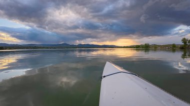 Rocky Dağları üzerinde fırtınalı bulutlar ve günbatımı - Lou, Colorado 'daki Boedecker Rezervuarında kano ya da kanodan POV manzarası
