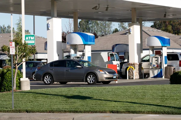 在没有人在场的情况下坐在加油站水泵旁的几辆车 — 图库照片