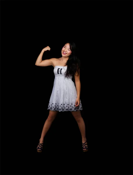 魅力的な日系アメリカ人女性が黒の背景に片腕の中でビスケットの筋肉を示すドレスに立って — ストック写真